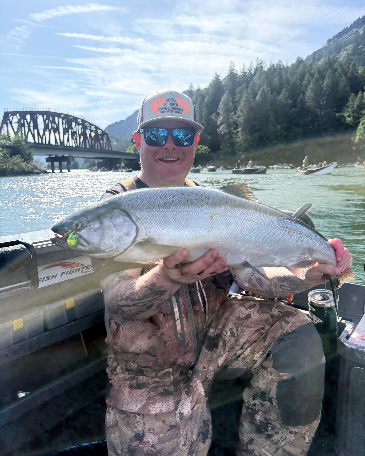 Angler holding a chrome spring chinook on the boat below a railroad bridge