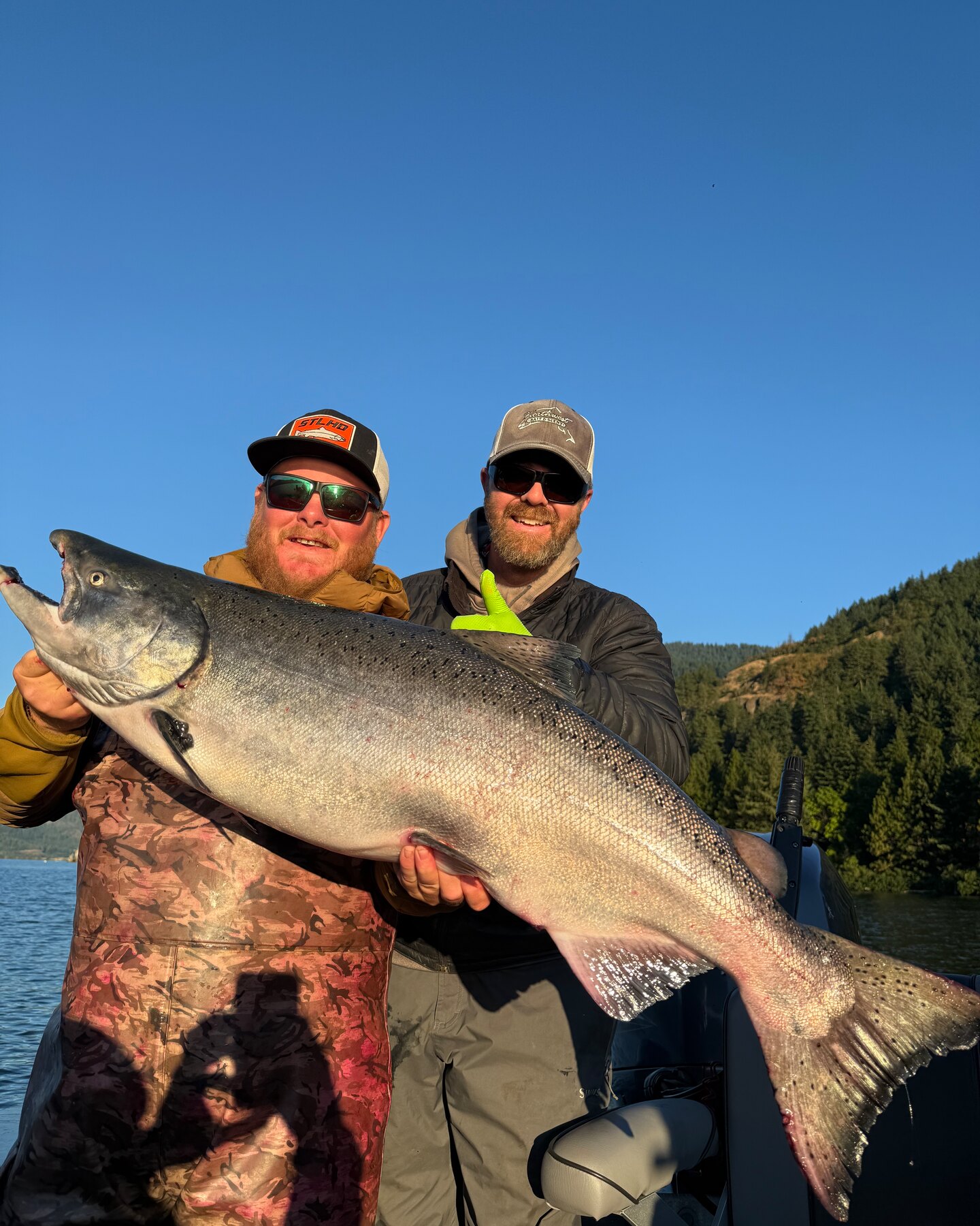 Two anglers holding a giant fall chinook salmon on the boat
